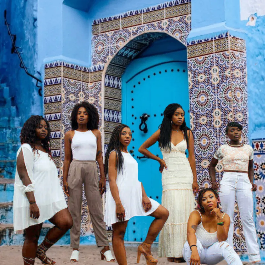 A diverse group gathered in front of a richly tiled blue Moroccan doorway